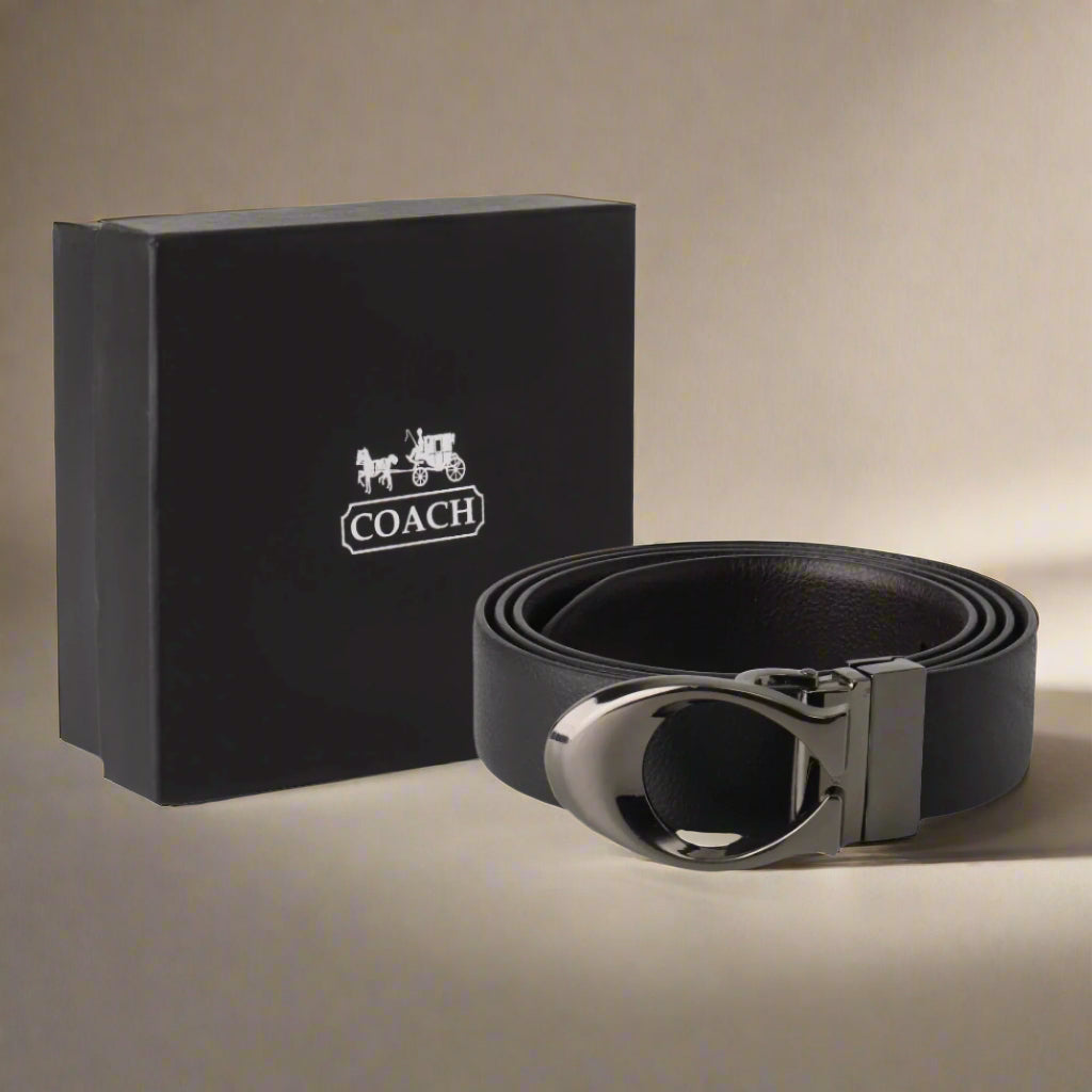 Coach black leather belt with silver buckle next to a Coach branded box on a gray background